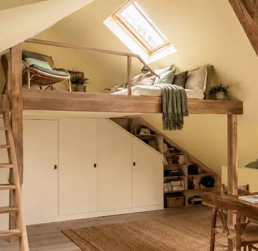 Mezzanine sous pente, ambiance cosy : fauteuil et canapé, murs jaunes, poutres bois, rangement et bureau