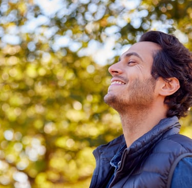 man with eyes closed smiling in nature