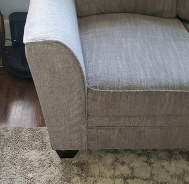 Close-up of a light gray textured fabric sofa on a plush area rug in a modern living room.