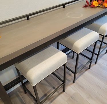 Modern wooden console table with three upholstered stools tucked underneath for space-saving seating.