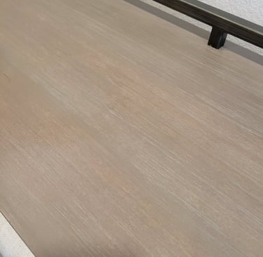 Close-up of a light brown weathered wood tabletop with visible grain.