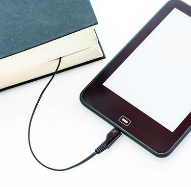 An iPad is connected to a hardbound book with USB cable from the iPad to the hardbound book. 