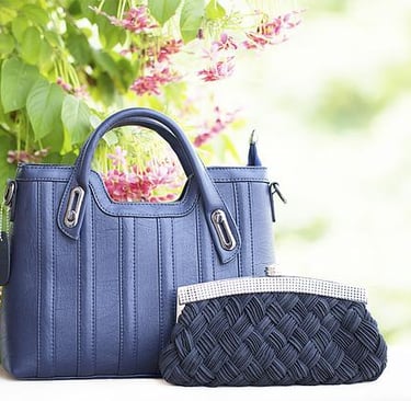 Navy blue handbag and matching clutch displayed outdoors.
