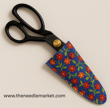 A pair of black tailor’s shears with gold pivot detail partially enclosed in a handmade fabric case.