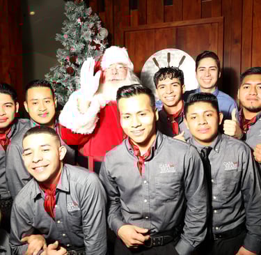 a group of people standing around a man dressed in a santa clause costumeat Casa Do Brazil
