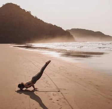une femme faisant une posture de yoga à la plage