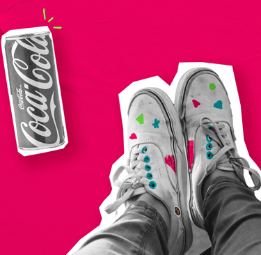os pés de uma pessoa e desenhos coloridos no tênis e uma lata de refrigerante em um fundo rosa