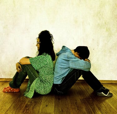 a man and woman sitting back to back on the floor