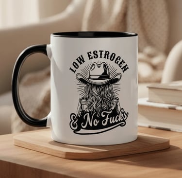 a mug with a woman wearing a cowboy hat and text that says "low estrogen & no fucks".