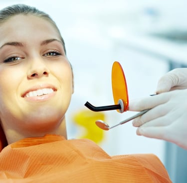 A smiling woman as a dentist holds instruments nearby.