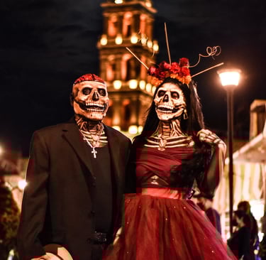 Couple in skull masks celebrating Day of the Dead in front of a Mexican cathedral.