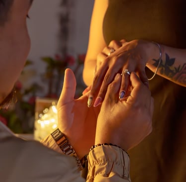 A man proposing by placing a diamond engagement ring on a woman's finger in a romantic setting.
