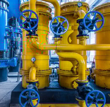 Tanques industriales de almacenamiento amarillos con válvulas de control azules y tuberías metálicas