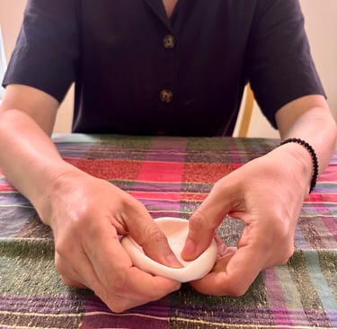 In an expressive arts therapy session, a person molds a clay ball into a bowl using their hands