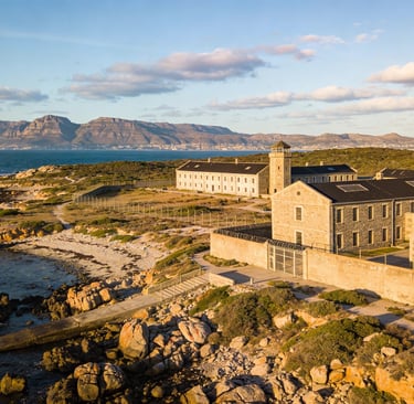 Aerial view of Robben Island Museum and prison buildings with Table Mountain in the background.
