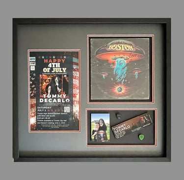 Framed shadow box displaying Boston band memorabilia, including a Tommy DeCarlo concert poster and ticket.