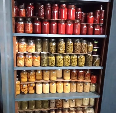 Basement shelving unit with doors open, rows of home-canned jars organized by type.