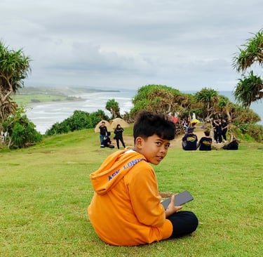 a man sitting on a hill with a handphone