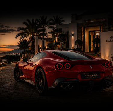 Red Ferrari 812 Superfast luxury sports car parked outside a modern villa at sunset.