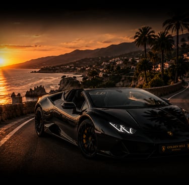 A black Lamborghini Huracan convertible parked on a coastal road at sunset with palm trees.