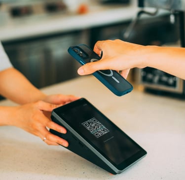Customer using a smartphone for a contactless QR code mobile payment at a cafe POS terminal.