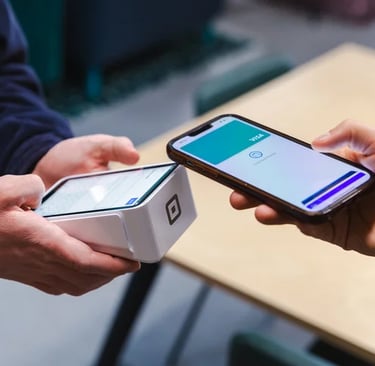 Customer using a smartphone for a contactless mobile payment at a Square card terminal.