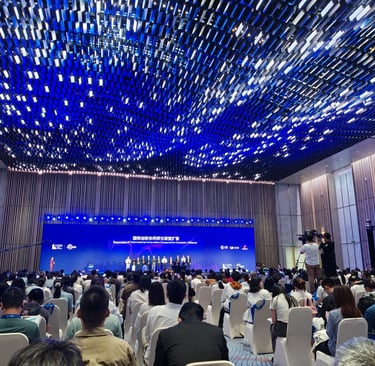 Audience at an international innovation conference under a blue light installation in a modern hall.
