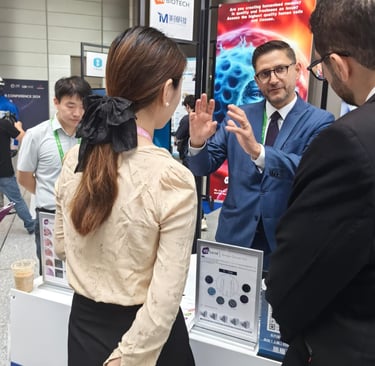 A biotech representative in a suit presents human cell research at a professional medical conference exhibit.