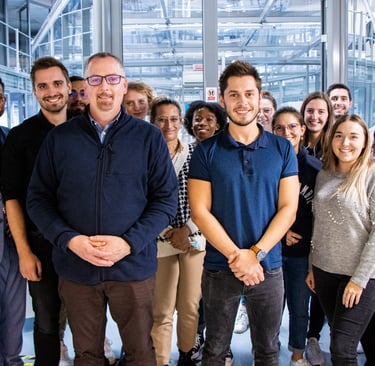 A diverse group of smiling professional office colleagues posing for a team photo in a modern workplace.