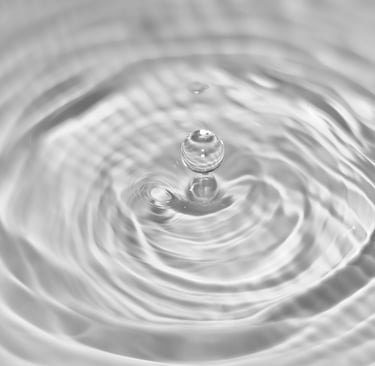 Water droplet creating gentle ripples in clean water, symbolizing purity and sustainable washing.