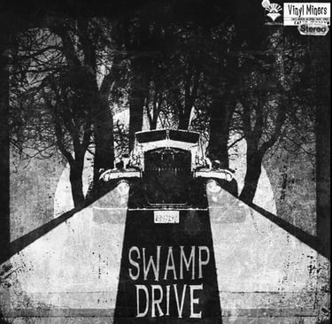 Vintage black and white Swamp Drive vinyl album cover art featuring a car on a road between dark trees.