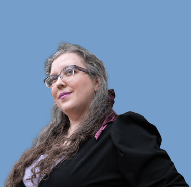 Woman with glasses in a black blazer, wearing a burgundy hairbow