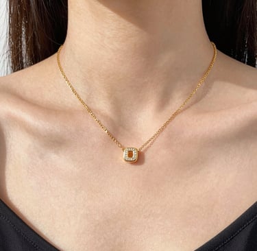 Close-up of elegant gold chain and minimalist ring on a soft black velvet background.