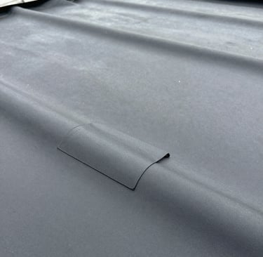 Side view of a repaired EPDM rubber roof section under bright daylight.