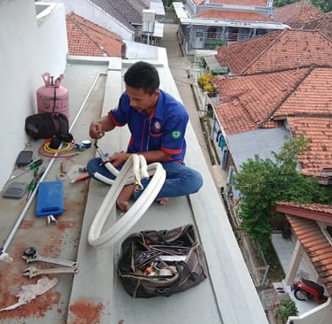 seorang teknisi sedang service sekalian pasang ac di rumah sentul city bogor