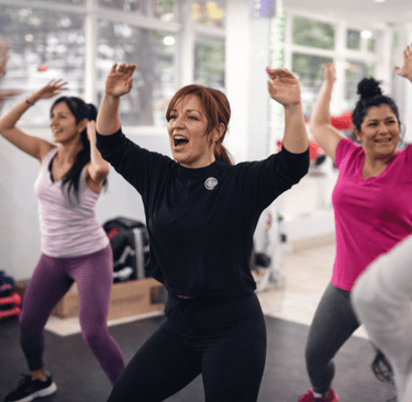  Grupo de mujeres sonriendo y bailando durante una animada clase de zumba fitness