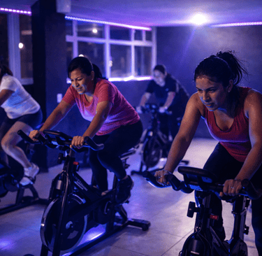 grupo de mujeres en una clase de spinning en interiores oscuros con iluminación de neón violeta