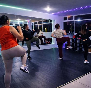 Grupo de mujeres en una clase de Tae Bo de alta intensidad en un gimnasio moderno con luces neón