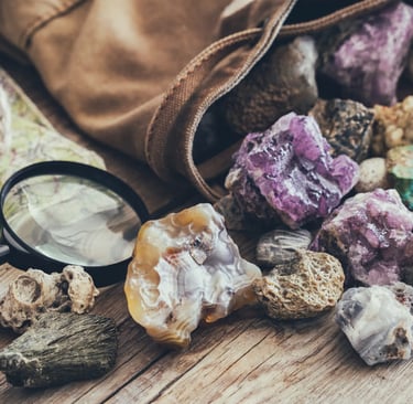 Piedras preciosas de amatista morada en bruto en una bolsa de lona, ​​y lupa