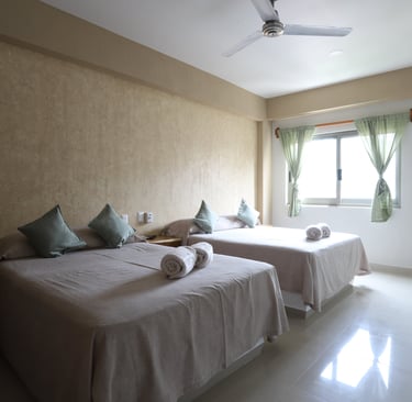 Habitacón con dos camas matrimoniales y una ventana de fondo