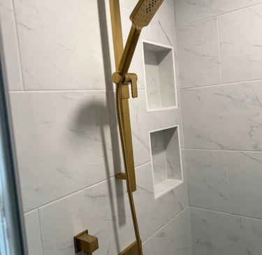 Modern bathroom shower featuring brushed gold fixtures on white porcelain tiles.