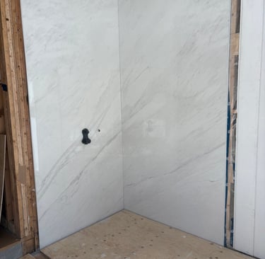 White marble pattern porcelain slab wall panels installed in a bathroom shower.