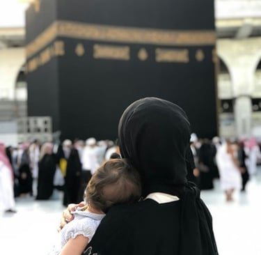 A muslim mother holding her baby while facing the Holy Kaaba in Mecca for pilgrimage.