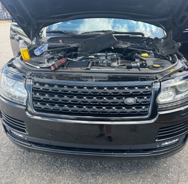 Black Land Rover Range Rover with an open hood undergoing engine repair and maintenance.
