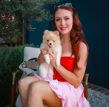 Founder Megan Patricia Keyser holding Liebe the Pomeranian in a West Hollywood outdoor lounge.