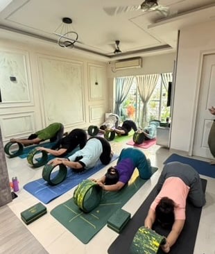 Yoga group performing Uttana Shishosana (Extended Puppy Pose) under instructor guidance