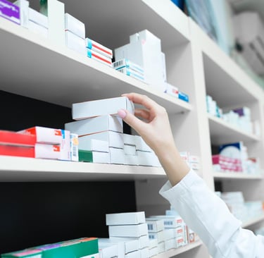 Un farmacéutico alcanza una caja de medicamentos en un estante lleno de productos de una farmacia