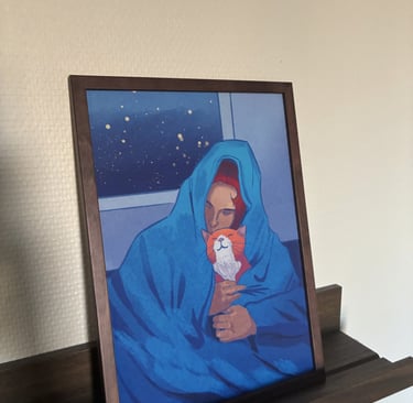 Framed painting of a woman and her orange cat snuggled under a blue blanket at night.