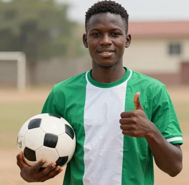 A young male soccer player in a green and white jersey holding a football and giving a thumbs up.