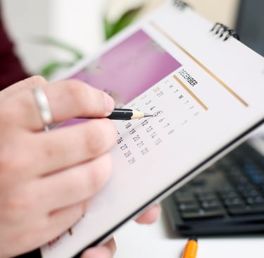 A person circling a date on a monthly calendar